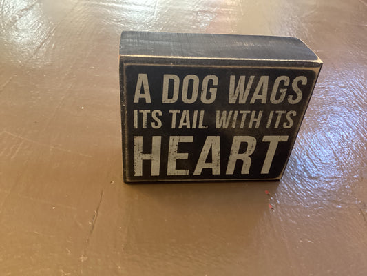 A dog wags it’s tail with it’s heart box sign